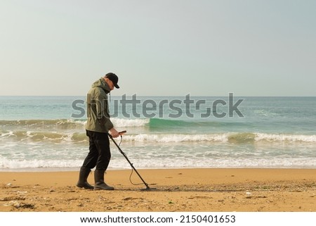 A man with a metal detector and a shovel on the seashore. A treasure hunter with a metal detector. A man is looking for a treasure. High quality photo