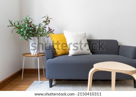 White and yellow pillows on a grey sofa with carpet in Scandinavian living room interior.