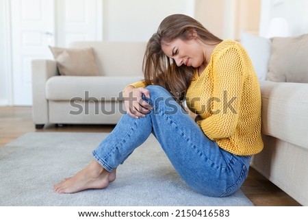 Woman lying on floor looking sick in the living room. Beautiful young woman lying on bed and holding hands on her stomach. Woman having painful stomachache on bed, Menstrual period Royalty-Free Stock Photo #2150416583
