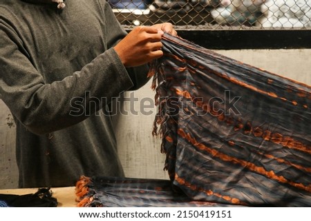 Mn hands folded the fabrics in tailor's workshop. Folded squared pattern sarung, sarong