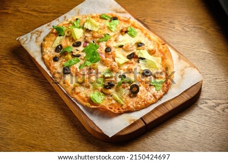 Pizza with bacon olives and tomatoes on a wooden table,
