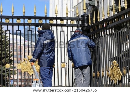 Workers paint the metal fence of Defense Ministry of Russia in Moscow. Repairs before the Victory Day celebration