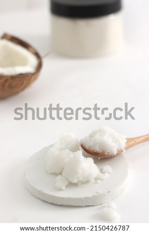 scrub in wood spoon with jar and coconut on white background. Home spa treatment concept, organic cosmetic. Vertical photo. Copyspace