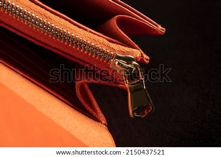 Part of a leather wallet and purse on a black background.