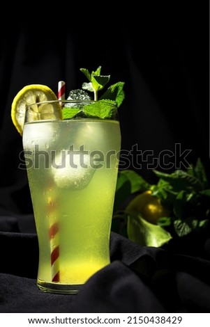 Fresh Homemade Lemonade or mojito cocktail with lemon, mint and ice on dark bacground