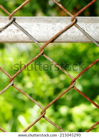 old abandoned rustic steel metal mesh fence outdoor under natural sunlight with green environment background