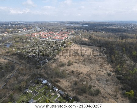 A drone shot over cityscape of the buildings with trees in a big landscape under cloudy sky