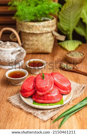 Kue ku or sometimes called as red tortoise cake is Indonesian chinese influcenced cake popular during Chinese New Year. Served on wooden table with some tea pot and glass as ornaments. Selective focus Royalty-Free Stock Photo #2150461211