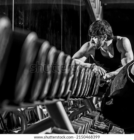 A grayscale shot of a fit athletic muscular Caucasian man working out at the gym Royalty-Free Stock Photo #2150468399