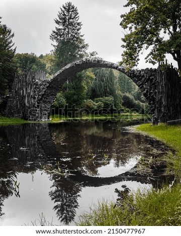 Photos of the Rakotzbrucke with perfect reflections on an overcast day during spring with the trees in full bloom