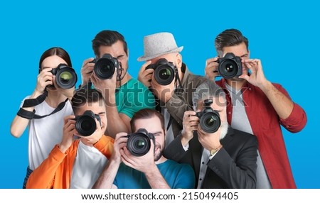 Group of professional photographers with cameras on turquoise background