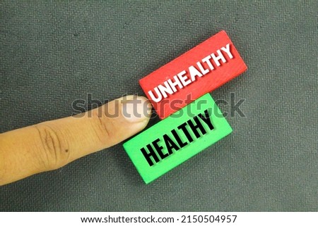 colored wooden boards with the words HEALTHY and UNHEALTHY concept
