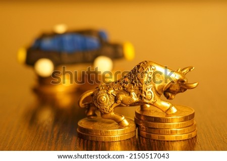 A metal bull with coins on the background of a toy car.