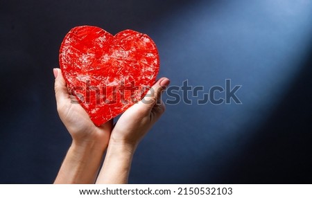 Hands holding red heart as symbol of love, care and support. Romantic gift for Valentine day