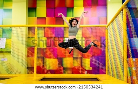 Pretty girl kid jumping on trampoline and happy at playground park. Female teenager in motion during active entertaiments Royalty-Free Stock Photo #2150534241