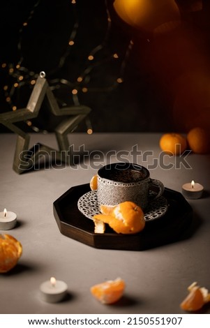 Holiday festive mulled wine aromatic fruit tea with orange tangerines and candles. Ceramic cup mug with hot beverage, cinnamon sticks.
