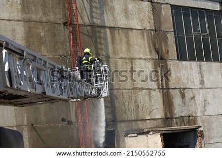 A firefighter from a car ladder truck extinguishes a fire in an industrial hall in the area of ​​a former coal mine