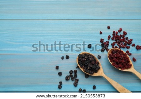 Dried red and black currant berries on light blue wooden table, flat lay. Space for text