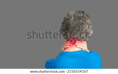 Cervical dystonia disease. Back view of a senior woman suffering neck pain and neck tilt while standing against a gray background. Neuralgia of the occipital nerve. Medical and healthcare concept Royalty-Free Stock Photo #2150554167
