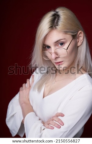 Stylish girl with blond hair, smiling cutely, posing, on red background, glasses, eyeglasses, blazer