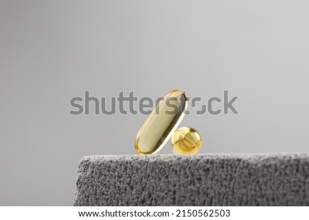 Yellow oil capsules with vitamin D on grey background. Omega 3 tablet. Healthy diet concept Royalty-Free Stock Photo #2150562503