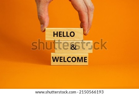 Hello and welcome symbol. Concept words Hello and welcome on wooden blocks. Businessman hand. Beautiful orange table orange background. Business hello and welcome concept. Copy space.