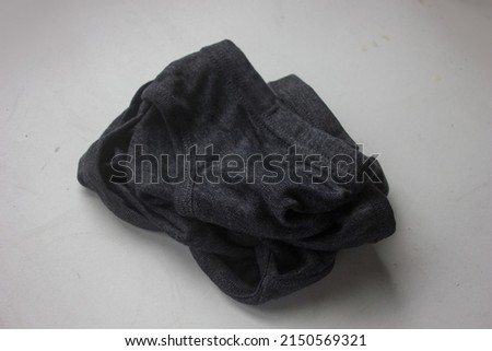 An old used wrinkled cotton black dirty male underpants are isolated on the home floor background, for a household advertising presentation.