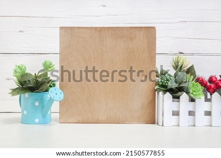 Wooden sign mockup on a light background with flowers. Square wood sign on the table against a light wall.