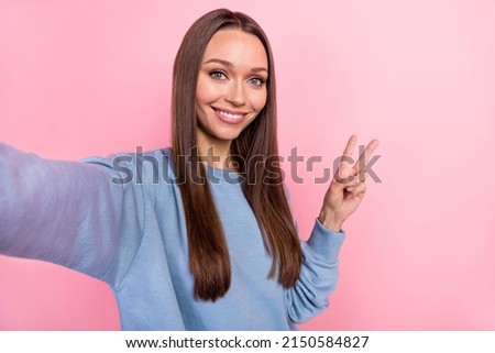 Self-portrait of attractive girly cheerful girl showing v-sign rest isolated over pink pastel color background