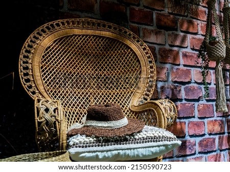 Cozy summer garden chair in rattan and in soft morning light on the terrace, inviting to relaxation. Shallow depth of field.