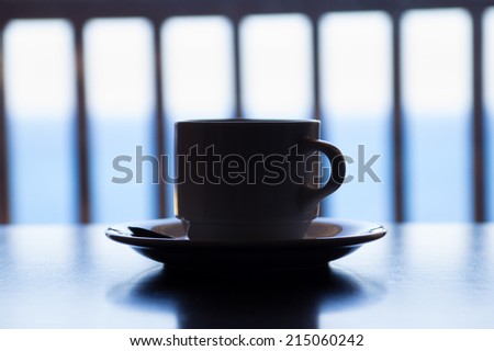 dark picture of cup of coffee on wooden table over sea view