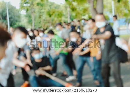 Royalty high quality free stock photo Unidentified a group of people playing a game of tug of war, a team building game with blurred bokeh background. Green lifestyle after the Covid pandemic.