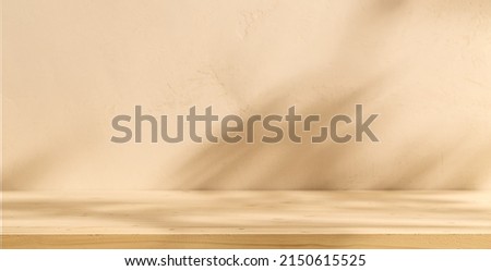 Mock up for presentation, branding products, cosmetics, food or jewellery. Empty table on bright brown wall background. Composition with leaves shadow on the wall and wooden desk.  Royalty-Free Stock Photo #2150615525