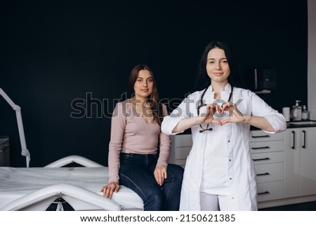Smiling beautiful young indian ethnicity female doctor cardiologist showing heart symbol with fingers, expressing love and support to patients, healthcare medical help charity donation concept.
