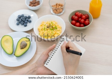 Diet, Dieting hand of asian young woman, girl write diet plan nutrition on table is different food ingredients in the green. Nutritionist of healthy, nutrition of weight loss, health care people. Royalty-Free Stock Photo #2150624001