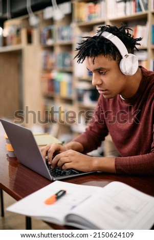 African American student e-learning on a computer in library.