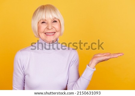 Photo of mature lady hold hand product promo offer advertise choice isolated over yellow color background