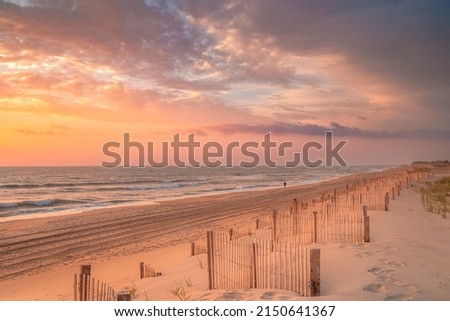 Lone individual going for an early morning walk at sunrise along the Outer Banks of North Carolina near Nags Head Royalty-Free Stock Photo #2150641367