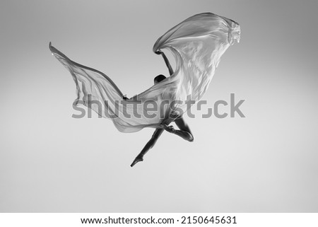 Like butterfly. Black and white portrait of graceful ballerina dancing with fabric, cloth isolated on grey studio background. Grace, art, beauty, contemp dance concept. Weightless, flexible actress Royalty-Free Stock Photo #2150645631