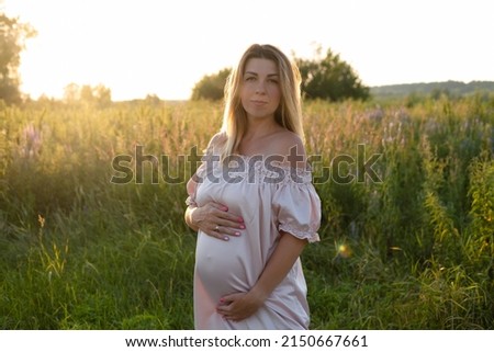 tender pregnancy portrait on sunset. expecting mother to be outside in pink dress. Beautiful tender mood photo of pregnancy