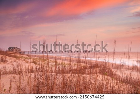 Sunrise over the beach and a fishing pier along the Outer Banks in North Carolina near Nags Head Royalty-Free Stock Photo #2150674425