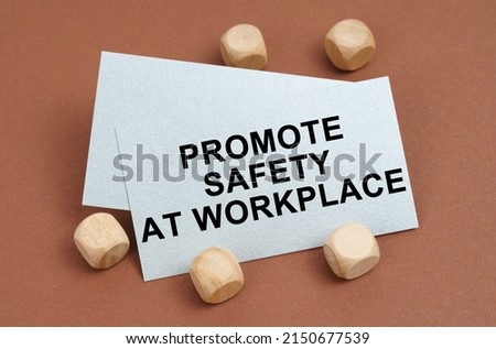 The concept of industrial safety. On a brown surface, wooden cubes and a business card with the inscription - Promote Safety at Workplace