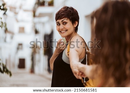 Woman holding her partner's hand as she turns to look at her and smile. Lifestyle