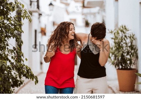 Couple of friends doing tourism during the summer. Walking and laughing around a small white village. Lifestyle