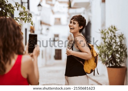 
Woman taking photos with the smartphone of her partner while they spend the summer together. Lifestyle