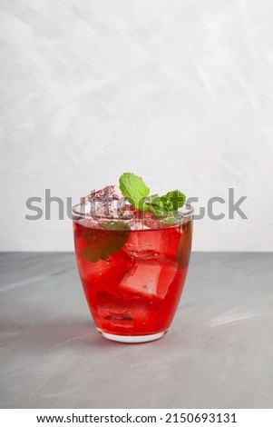Iced fruit red cocktail or cold watermelon drink with hibiscus and mint leaf. Refreshing summer drink. Grey background, copy space. Royalty-Free Stock Photo #2150693131