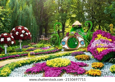 Famous flower exhibition in Kiev on Singing Field,Ukraine. Natural landscape design with flower beds, fairy tail house,trimmed bushes in city park at spring. home green garden in courtyard.