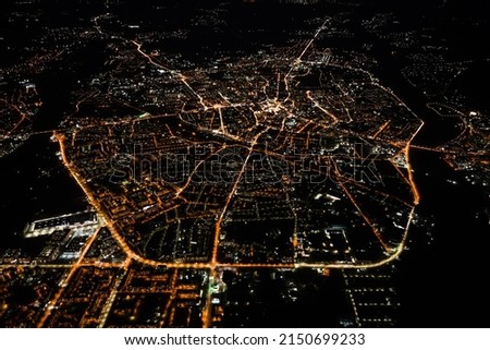 Aerial view from airplane window of buildings and bright illuminated streets in city residential area at night. Dark urban landscape at high altitude Royalty-Free Stock Photo #2150699233