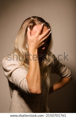 A young woman covering her face in grief lowered her head down. Royalty-Free Stock Photo #2150701761