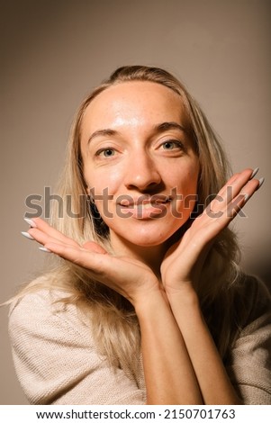 A young woman holds her palms near her face and smiles Royalty-Free Stock Photo #2150701763